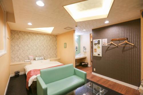 a hospital room with a bed and a green couch at ホテルロコズマウイ in Honjo