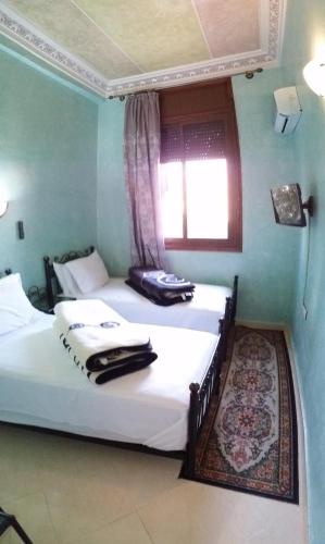 two twin beds in a room with a window at Hotel Espace Tifawine in Tafraoute