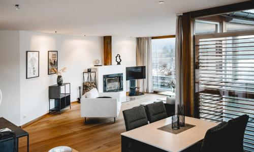 a living room with a couch and a tv at Seehotel Brandauer's Villen in Strobl
