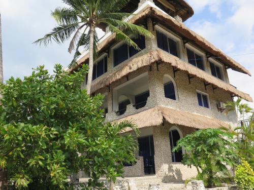 an old house with a thatched roof and a palm tree at The Wild Orchid Resort - Moalboal in Moalboal