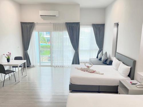 a bedroom with two beds and a table and a dining room at GRAND PA Hotel&Resort Lamphun Chiang Mai in Lamphun