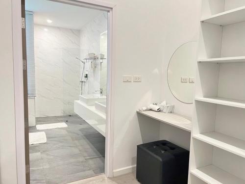a white bathroom with a glass shower and a black suitcase at GRAND PA Hotel&Resort Lamphun Chiang Mai in Lamphun