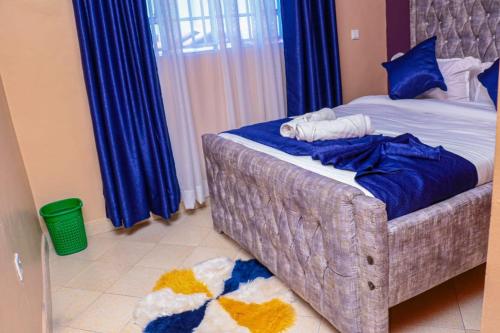 a bedroom with a bed with blue sheets and blue curtains at Memento airb&bs apartments in Nakuru