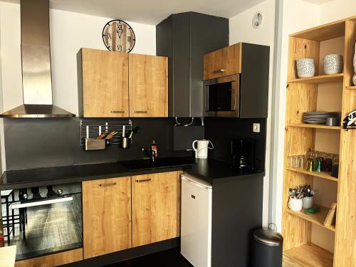 une cuisine avec des comptoirs noirs et des armoires en bois dans l'établissement l'Armazan - studio pieds de piste Plat d'Adet, à Saint-Lary-Soulan