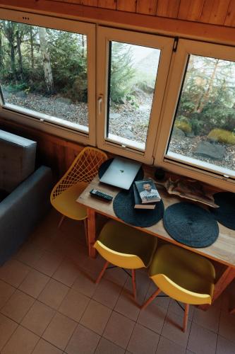 a room with a table with a laptop and two windows at Domki na Widoku in Lubomierz