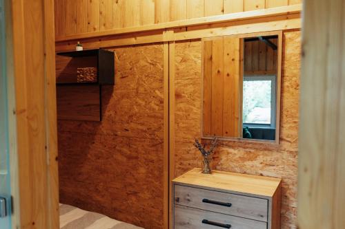 a bathroom with a wooden wall with a mirror and a dresser at Domki na Widoku in Lubomierz