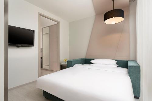 a bedroom with a white bed and a flat screen tv at Hyatt Place Bangkok Sukhumvit 1 in Bangkok