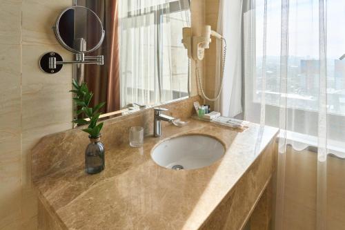 a bathroom with a sink and a mirror and a window at Kainar Hotel in Shymkent