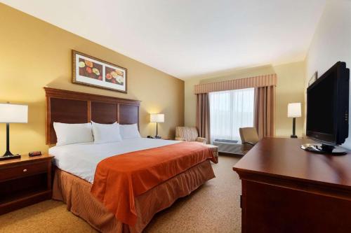 a hotel room with a bed and a flat screen tv at Country Inn & Suites by Radisson, Texarkana, TX in Texarkana - Texas