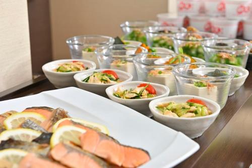 a table with a plate of food and bowls of food at Saijo Urban Hotel in Saijo