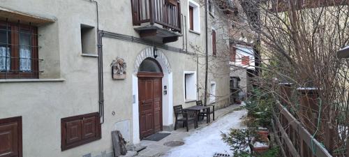 an alley with a building with a door and a table at Casa Grande appartamento Marianna in Pragelato