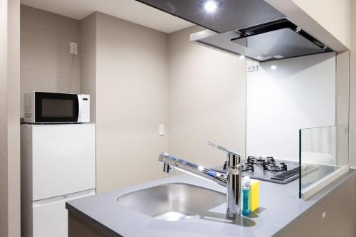 a kitchen with a sink and a microwave and a refrigerator at PREAS Nakano Arai in Tokyo
