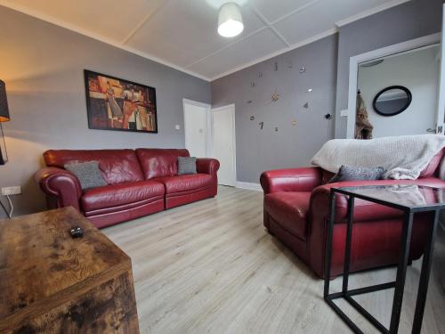 a living room with a red couch and a table at Canny Hyem in Birtley