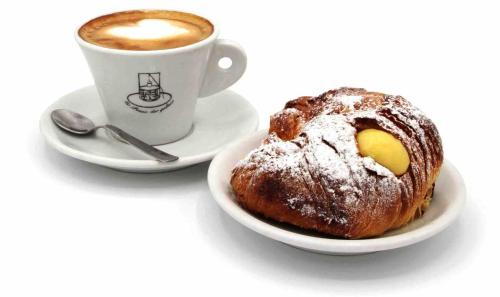 eine Tasse Kaffee neben einem Teller mit Gebäck in der Unterkunft Nuraghe Ruiu Piazzole campeggio Blue Holiday in Norbello