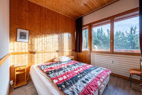 una camera da letto con letto in una camera in legno con finestre di Appartement 26 - 9 personnes a Les Allues