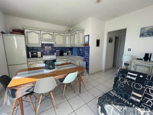 une cuisine avec des armoires blanches et une table et des chaises dans l'établissement Appartement 2 pièces cabine 5 couchages SAINT CYPRIEN SC610-002, à Saint Cyprien Plage