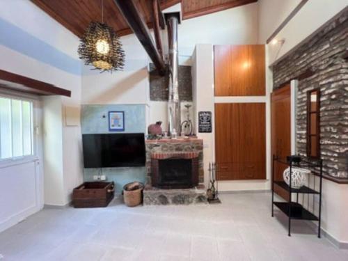 Una sala de estar con chimenea y televisión. en Finikous Cottage House-Agros, en Agros