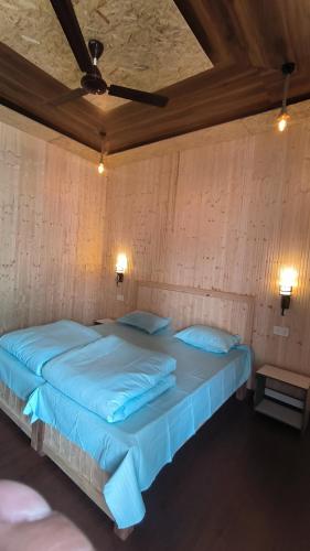 a large bed with blue sheets in a room at Himadri Homestay in Rudraprayāg