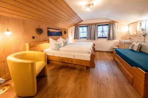 a bedroom with a large bed and a yellow chair at Ferienwohnungen Isarwinkel in Krün