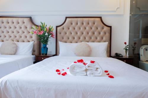 two towels on a bed with red rose pedals at Royal Hotel Trâu Quỳ in Thạch Cầu
