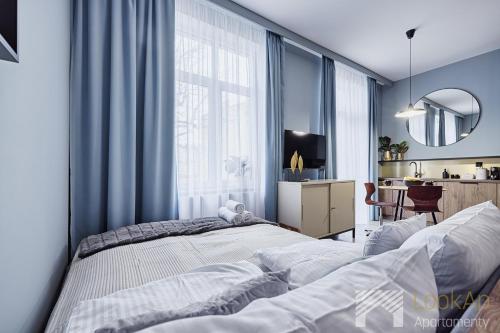 two beds in a bedroom with blue walls and a mirror at Kolorova Apart by LookAp - darmowy parking w centrum Łodzi! in Łódź