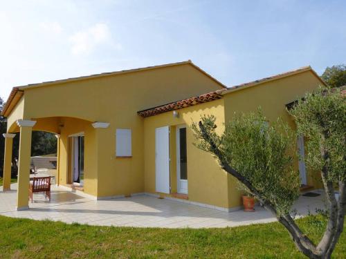 une maison jaune avec un patio et une table dans l'établissement Villa L'Argentière pour 6 personnes avec piscine et vue dégagée à La Londe-Les-Maures, à La Londe-les-Maures