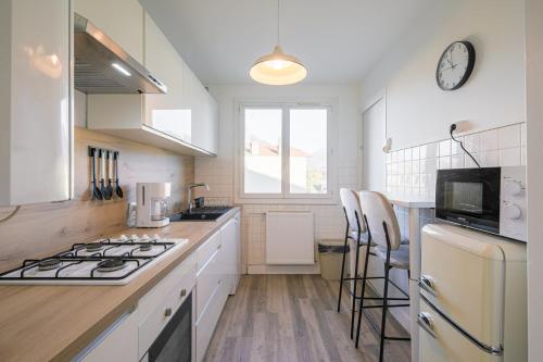 une cuisine avec des armoires blanches et un four à plaques de cuisson dans l'établissement Le Vercors - 6 couchages parking gratuit, à Fontaine