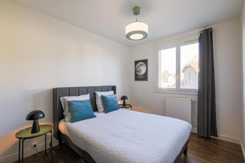 una camera da letto con un letto con cuscini blu e una finestra di Le Vercors - 6 couchages parking gratuit a Fontaine