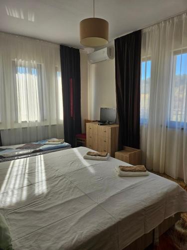 a bedroom with two beds and two windows at Бадевски рай-къща Надежда in Badewzi