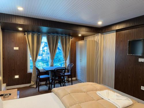 a bedroom with a bed and a table and chairs at Hotel Basera in Darjeeling