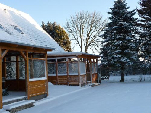 a building with snow on the ground next to a tree at Ferienwohnungen Kastenmüller in Westerdeichstrich