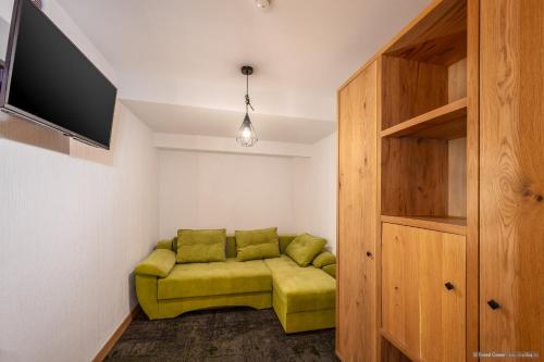 a living room with a green couch and a tv at Forest Green & Spa in Gura Humorului
