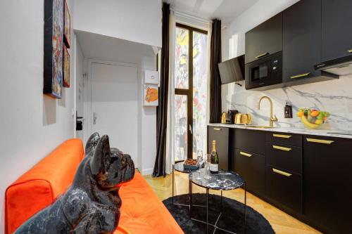 un chien assis sur un canapé orange dans une cuisine dans l'établissement 206 Suite Hermès - Superb apartment in Paris, à Paris