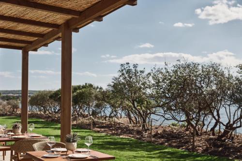a patio with tables and chairs and a view of the water at Zelia Halkidiki, part of Destination by Hyatt - Adults Only in Nea Potidaea