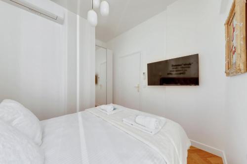a white bedroom with a bed and a tv at 208 Suite Guerlain - Superb apartment in Paris in Paris