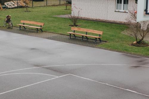 two park benches sitting in a parking lot at Bungalow mit Basketballplatz in Lemgo