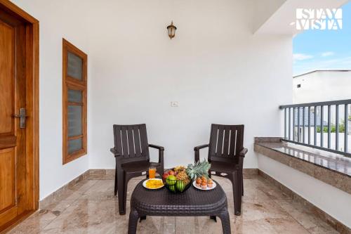two chairs and a table with fruit on a balcony at Whitewood Serene 5BHK Party House - Wayanad in Wayanad