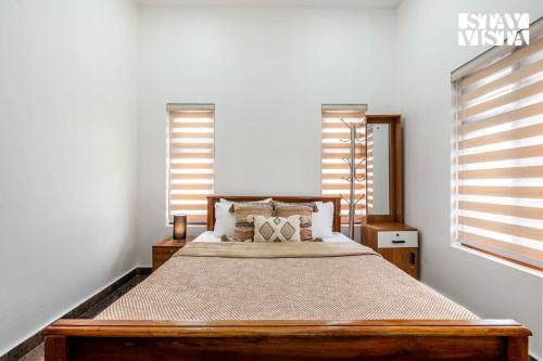 a bedroom with a large wooden bed with windows at Whitewood Serene 5BHK Party House - Wayanad in Wayanad