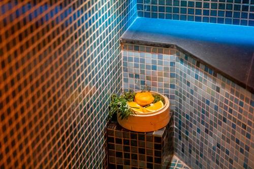 a tiled wall with a flower pot with an orange in it at Here and Now - Luxury Sea view & Spa Villa in Koh Samui 