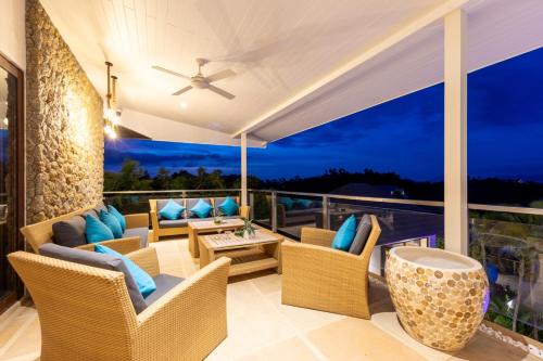 a balcony with wicker furniture and a view of the ocean at Here and Now - Luxury Sea view & Spa Villa in Koh Samui 