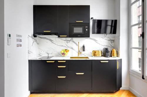 une cuisine avec des armoires noires et un four micro-ondes dans l'établissement 210 Suite Chanel - Superb apartment in Paris, à Paris