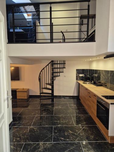 Il comprend une cuisine dotée de carrelage noir et d'un escalier en colimaçon. dans l'établissement Appartement Le Balnéo, à Nîmes