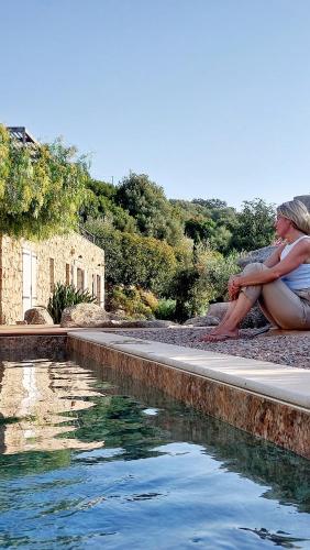 une femme est assise à côté d'une piscine dans l'établissement NOUVEAU VISTA CORSICA vue à couper le souffle, à Sotta