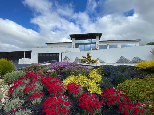 a house with a garden of flowers in front of it at Vertex Belvedere in Christchurch