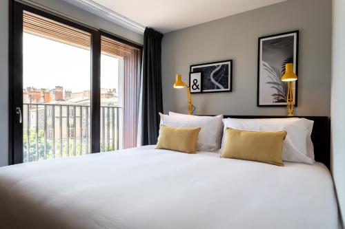a bedroom with a large white bed with a large window at Staycity Aparthotels Bordeaux City Centre in Bordeaux