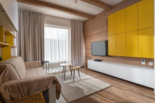 Una sala de estar con un sofá y un televisor. en TRITA SK - Apartmán Hrebienok resort 108 - Central location - Garage parking, en Starý Smokovec