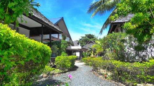 a path in front of a house with bushes at Pension Motu Iti in Pihaena