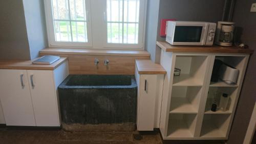 a kitchen with a sink and a microwave at La Madeleine in Nassogne