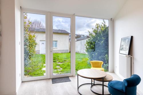 - un salon avec une grande fenêtre, une table et une chaise dans l'établissement La maison du Cavalier Bleu et son studio indépendant au coeur d'Yvetot !, à Yvetot