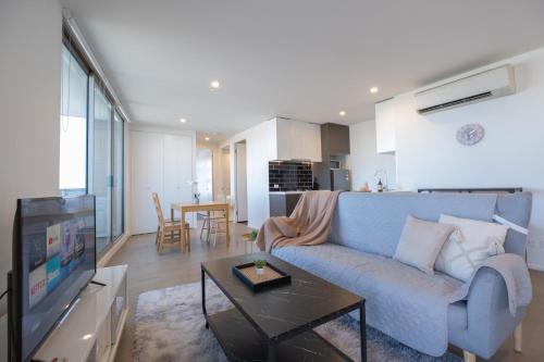 a living room with a blue couch and a television at Cityscape 2BR2BA Maribyrnong wifiparkbalcony in Maribyrnong